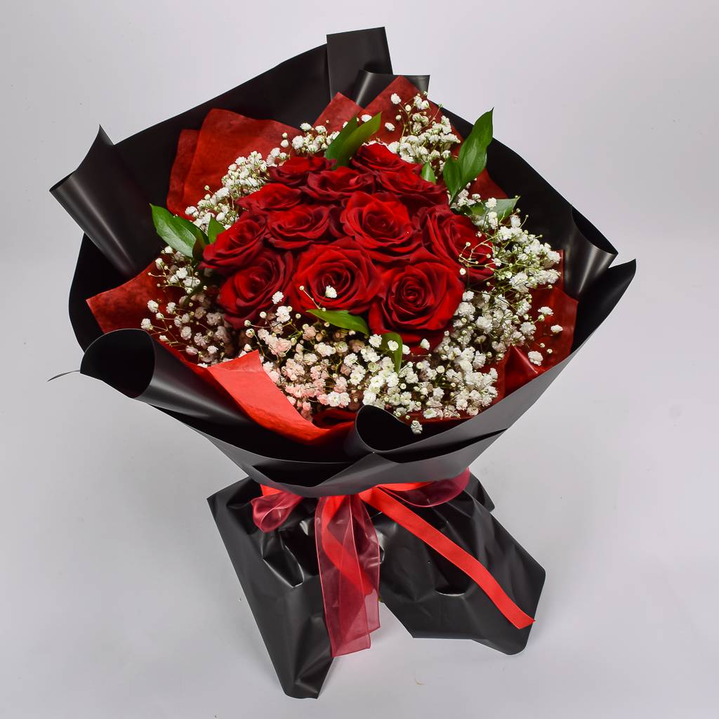 Bouquet of red roses with black and red wrap on a light gray background
