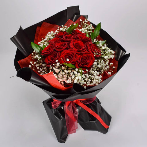 Bouquet of red roses with black and red wrap on a light gray background